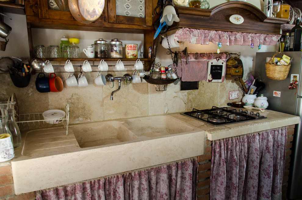 Immagine di una cucina shabby-chic style di medie dimensioni con lavello stile country, ante in legno bruno, top in pietra calcarea, paraspruzzi beige, paraspruzzi con piastrelle in pietra e pavimento in pietra calcarea