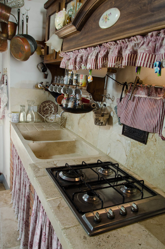 Esempio di una cucina shabby-chic style di medie dimensioni con lavello stile country, ante in legno bruno, top in pietra calcarea, paraspruzzi beige, paraspruzzi con piastrelle in pietra e pavimento in pietra calcarea