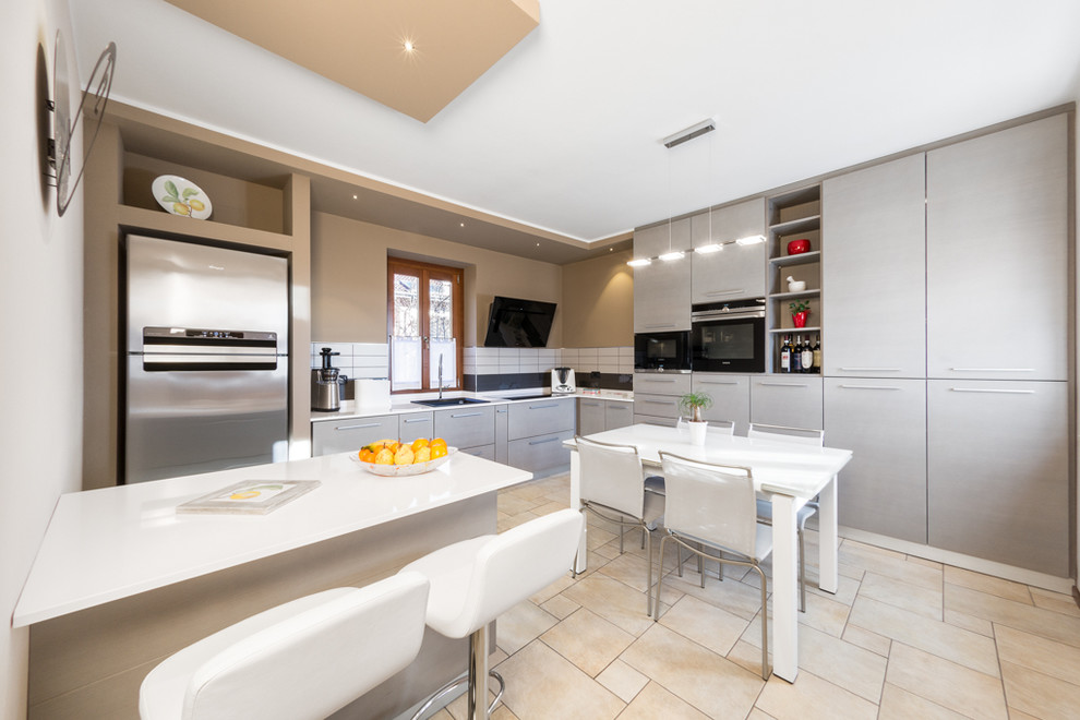 Bild på ett litet funkis kök, med en enkel diskho, släta luckor, grå skåp, vitt stänkskydd, rostfria vitvaror och en halv köksö