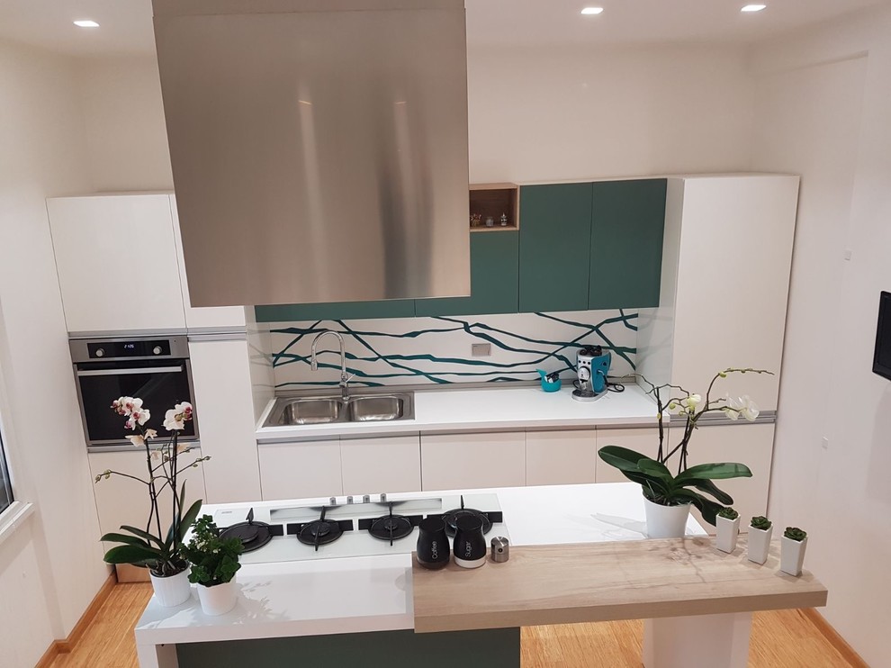 Esempio di una piccola cucina moderna con lavello da incasso, ante lisce, ante verdi, top in laminato, paraspruzzi a effetto metallico e pavimento in legno massello medio