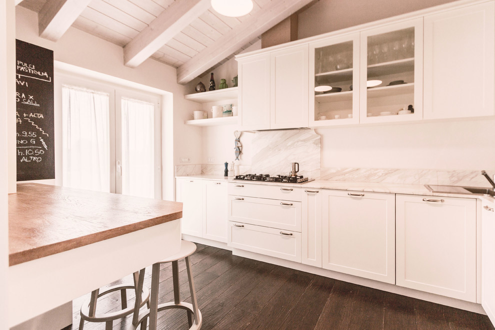 Modern inredning av ett avskilt, mellanstort vit linjärt vitt kök, med en dubbel diskho, luckor med infälld panel, vita skåp, marmorbänkskiva, vitt stänkskydd, stänkskydd i marmor, rostfria vitvaror, mörkt trägolv, en köksö och brunt golv