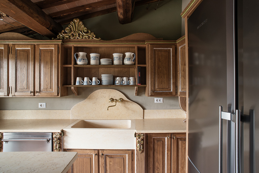 Lantlig inredning av ett stort kök, med en enkel diskho, bruna skåp, marmorbänkskiva och en köksö