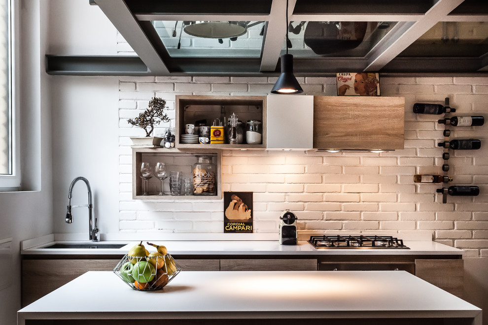 Foto di una cucina industriale con lavello sottopiano, ante lisce, ante in legno scuro, paraspruzzi bianco, paraspruzzi in mattoni, elettrodomestici neri e top bianco