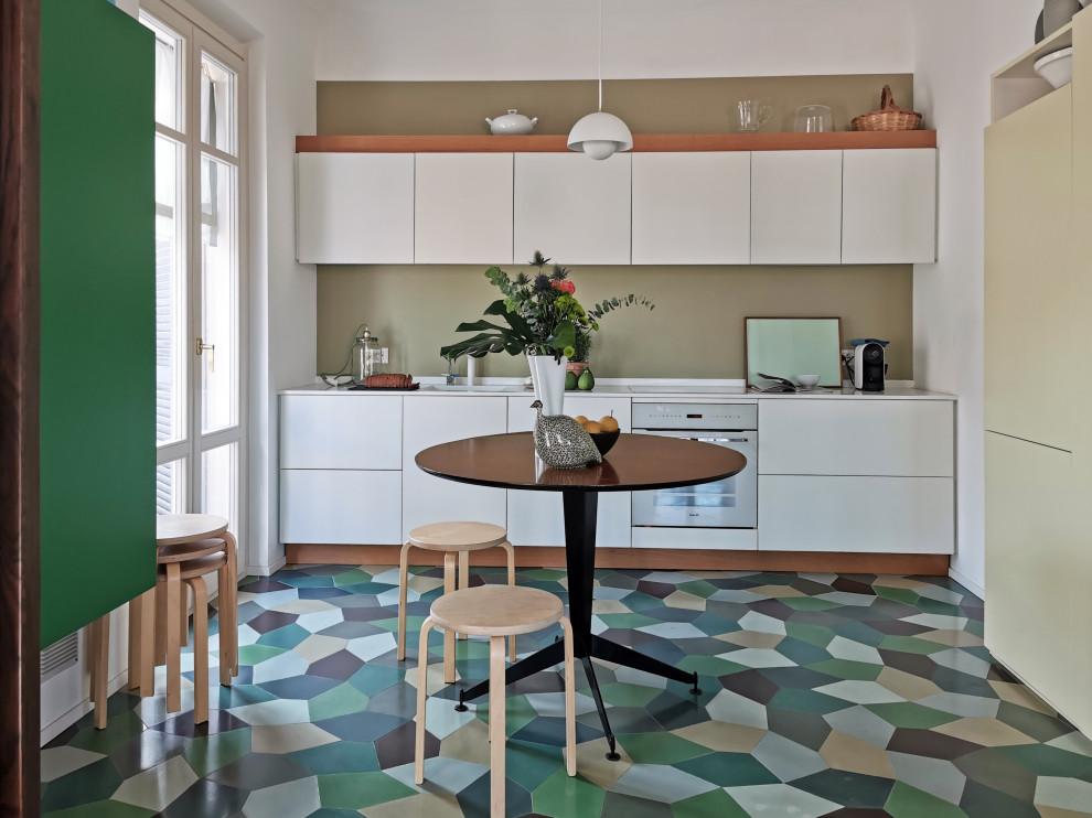 Inspiration for a contemporary l-shaped kitchen in Milan with flat-panel cabinets, white cabinets, white appliances, multi-coloured floors and white worktops.