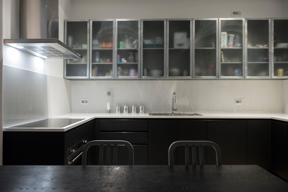 Ispirazione per una cucina design di medie dimensioni con lavello a doppia vasca, ante nere, top in superficie solida, paraspruzzi beige, paraspruzzi in marmo, elettrodomestici in acciaio inossidabile e top bianco