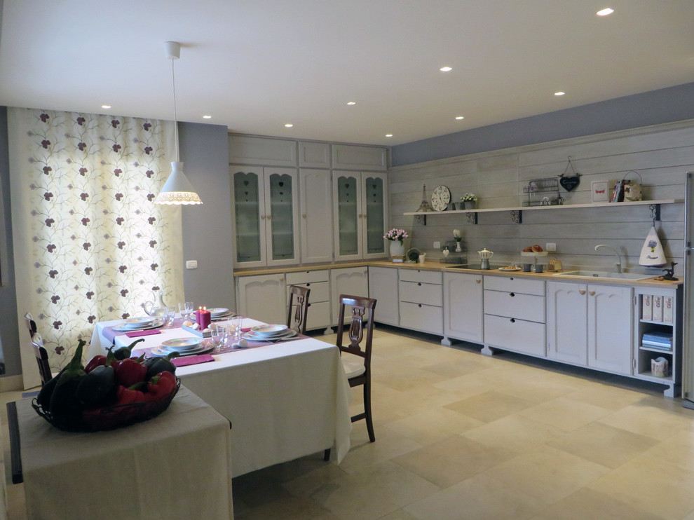 Offene Shabby-Style Küche in L-Form mit Waschbecken, Glasfronten, Arbeitsplatte aus Holz, Küchengeräten aus Edelstahl und Porzellan-Bodenfliesen in Catania-Palermo