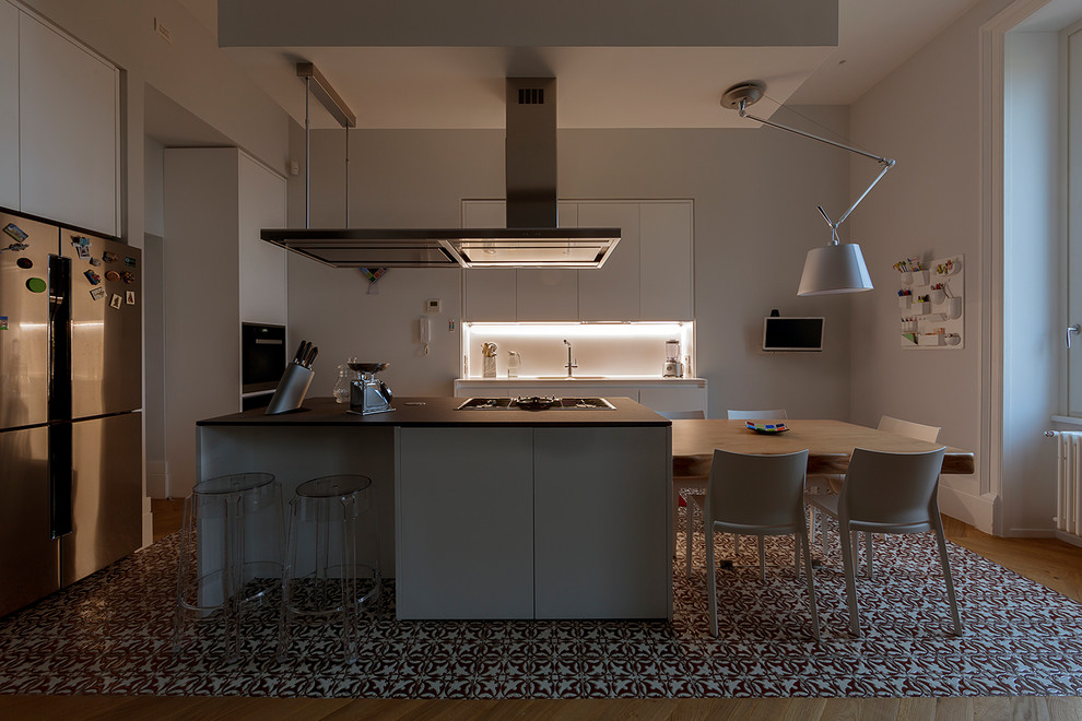 Exempel på ett mellanstort modernt grå grått kök, med en integrerad diskho, släta luckor, vita skåp, vitt stänkskydd, glaspanel som stänkskydd, rostfria vitvaror, klinkergolv i keramik, en köksö och flerfärgat golv
