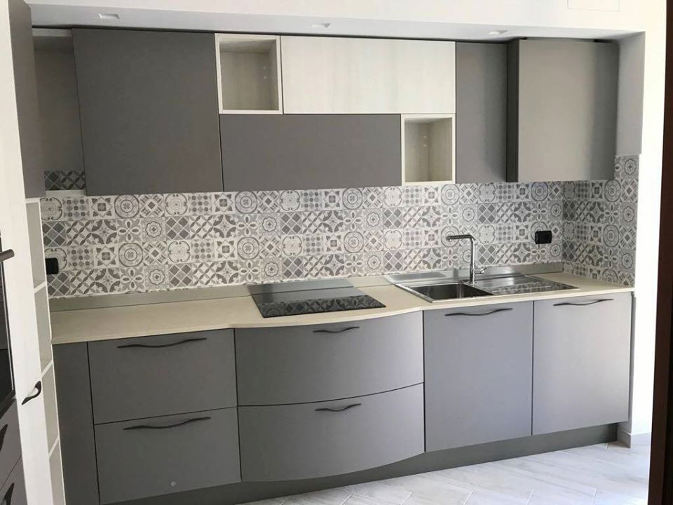 Inspiration for a medium sized modern l-shaped enclosed kitchen in Milan with a built-in sink, flat-panel cabinets, grey cabinets, laminate countertops, grey splashback, porcelain splashback, stainless steel appliances, porcelain flooring, no island, grey floors and grey worktops.