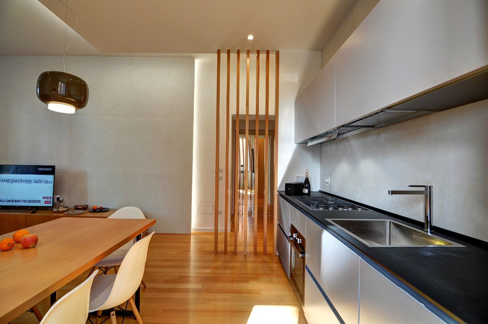 Esempio di una cucina design di medie dimensioni con ante lisce, ante grigie, paraspruzzi grigio, paraspruzzi con piastrelle di cemento, pavimento in legno massello medio, pavimento beige e top nero