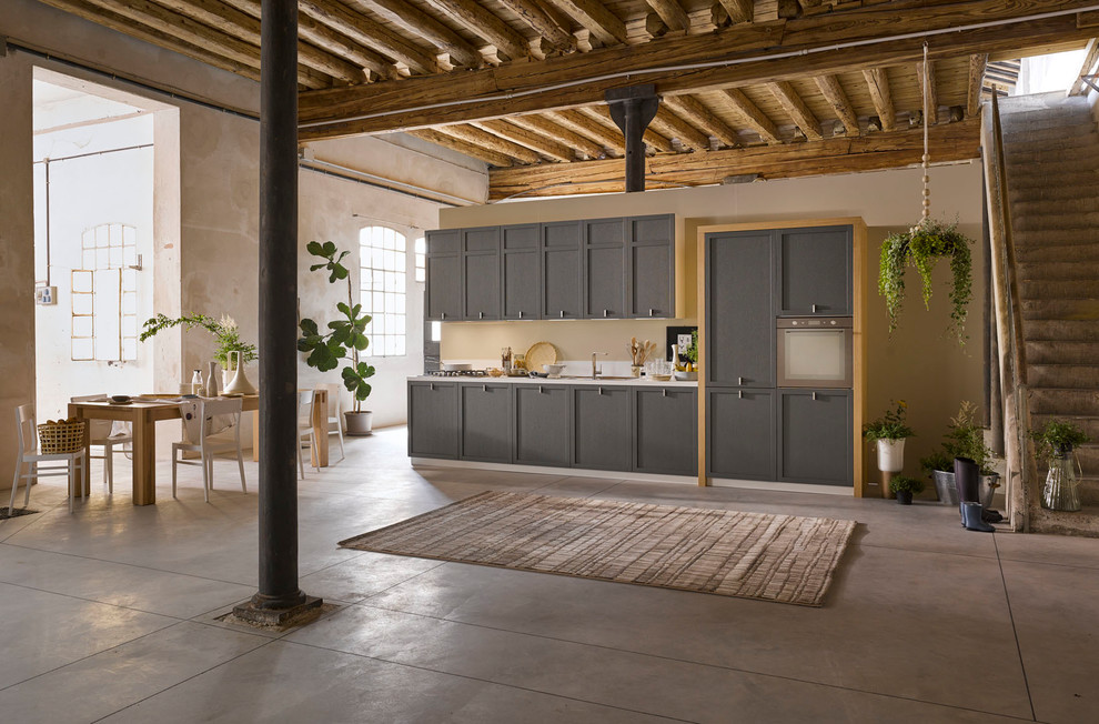 Immagine di una cucina country di medie dimensioni con paraspruzzi bianco e pavimento in cemento