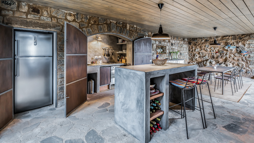 На фото: кухня в средиземноморском стиле с обеденным столом, столешницей из бетона, техникой из нержавеющей стали, островом, серым полом и серой столешницей