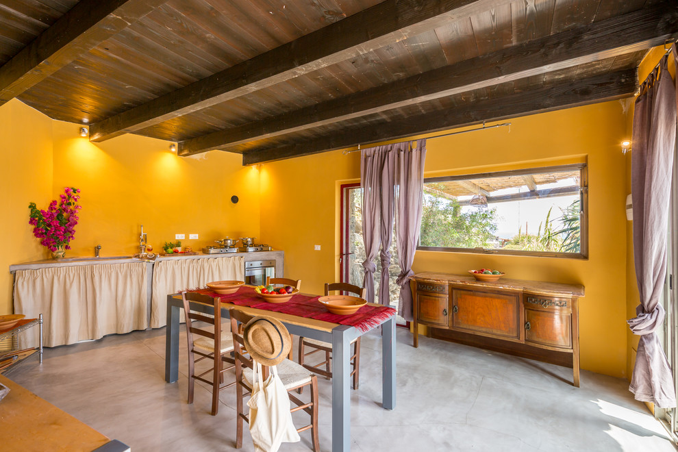 Idee per una cucina mediterranea con paraspruzzi giallo, pavimento in cemento, nessuna isola, pavimento grigio e top grigio