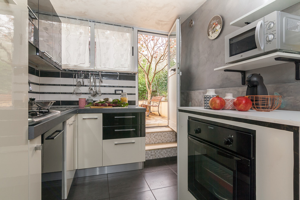 Esempio di una piccola cucina ad U design con ante lisce, ante nere, paraspruzzi bianco, elettrodomestici neri e pavimento grigio