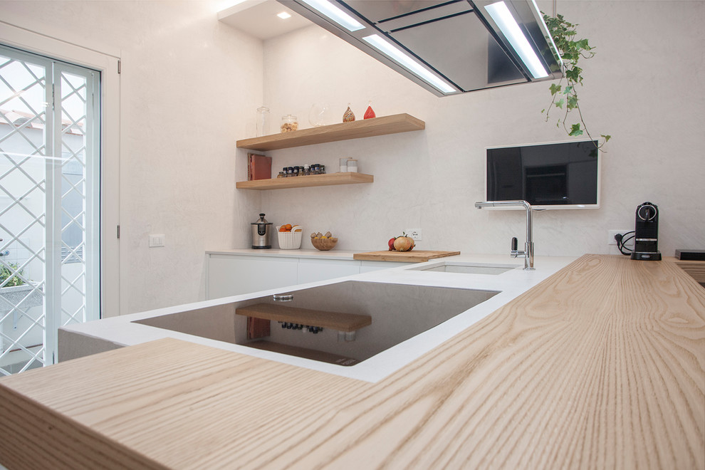 Foto di una cucina a L contemporanea con lavello sottopiano, ante lisce, ante bianche, penisola e top bianco