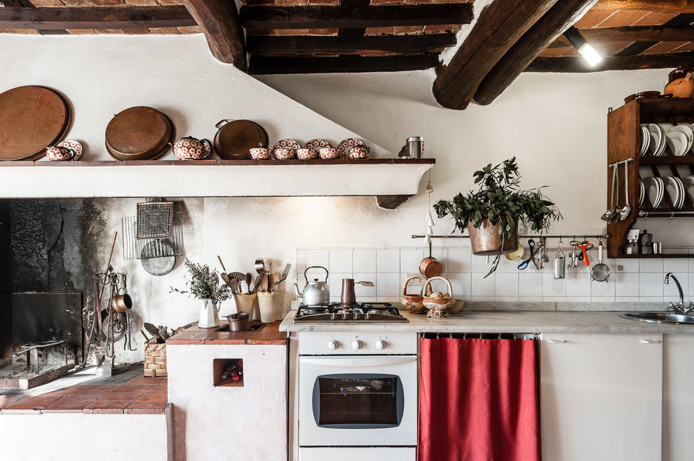 Landhaus Küche mit Einbauwaschbecken, flächenbündigen Schrankfronten, weißen Schränken und grauer Arbeitsplatte in Sonstige
