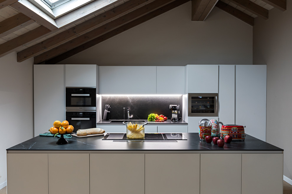 This is an example of a medium sized contemporary galley kitchen in Other with an integrated sink, flat-panel cabinets, white cabinets, black splashback, integrated appliances, an island and black worktops.