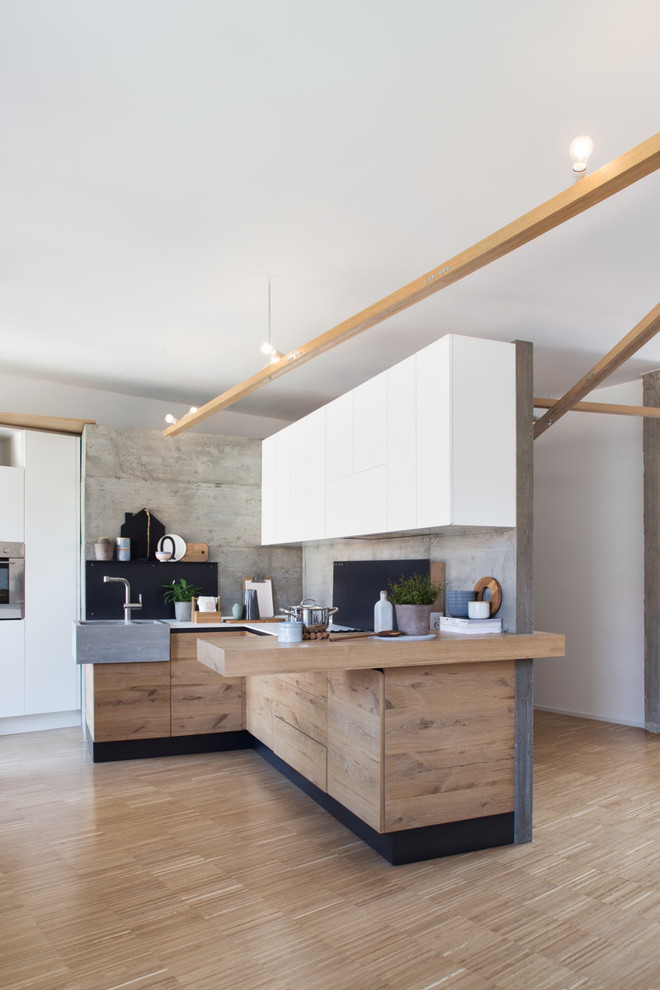 Esempio di una cucina minimal di medie dimensioni con ante lisce, ante in legno scuro, pavimento in legno massello medio e penisola
