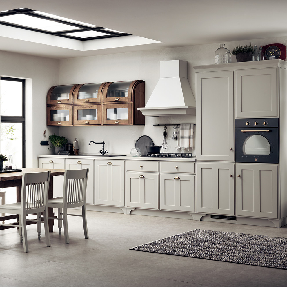 This is an example of a medium sized romantic single-wall open plan kitchen in Other with a single-bowl sink, recessed-panel cabinets, white cabinets, laminate countertops, no island, black appliances and grey worktops.