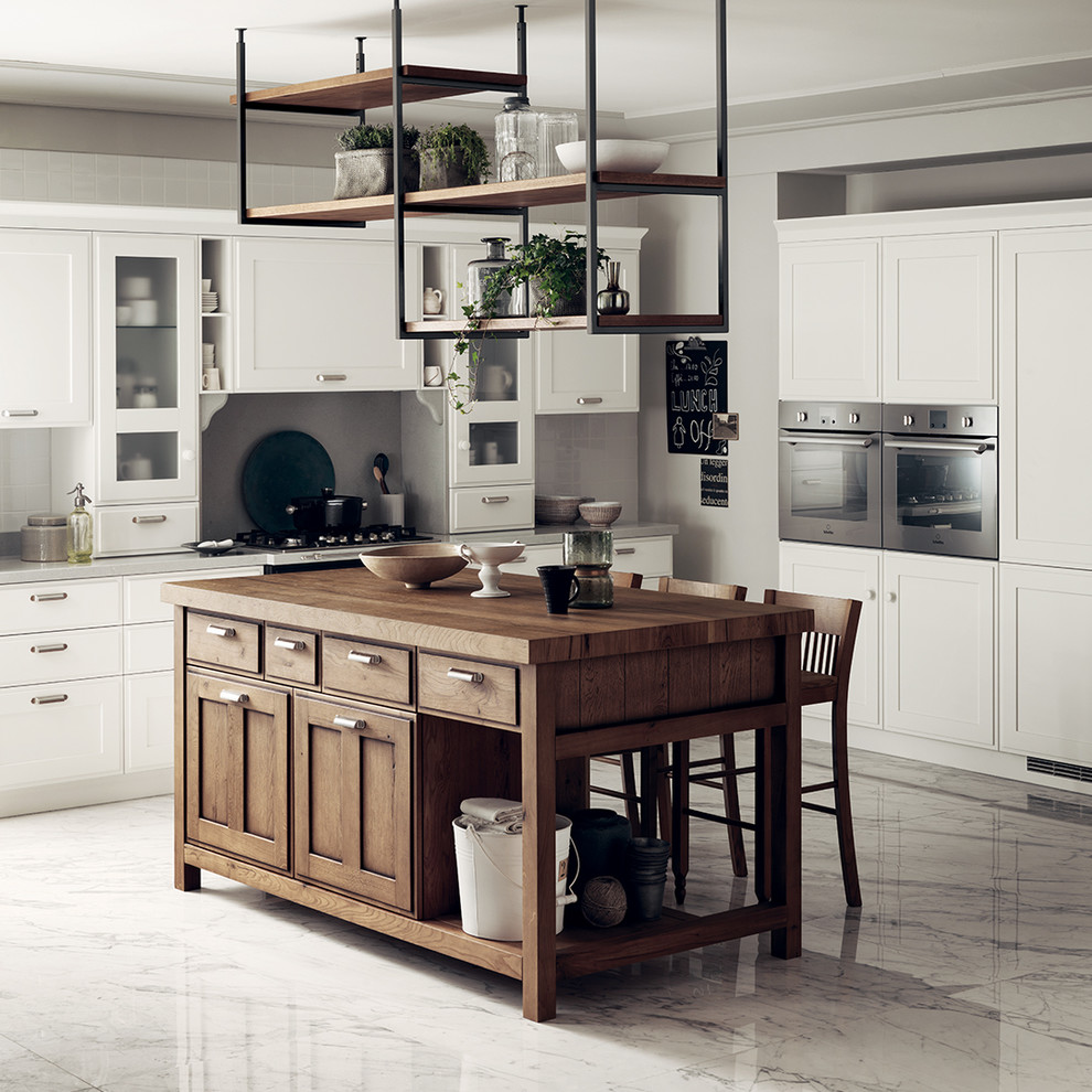 Large shabby-chic style single-wall open plan kitchen in Other with a single-bowl sink, recessed-panel cabinets, white cabinets, granite worktops, grey worktops and an island.