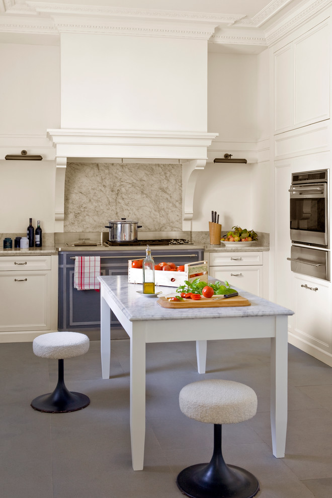 Klassisk inredning av ett mellanstort kök och matrum, med luckor med infälld panel, vita skåp, marmorbänkskiva, stänkskydd i sten och rostfria vitvaror