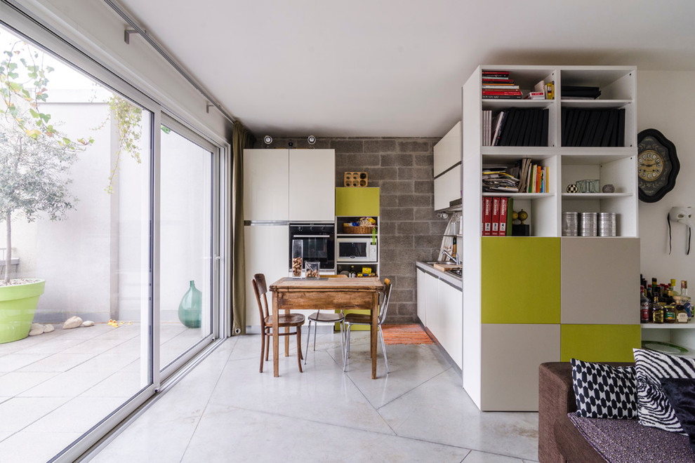 Стильный дизайн: прямая кухня-гостиная среднего размера в современном стиле с плоскими фасадами, белыми фасадами, черной техникой и мраморным полом - последний тренд