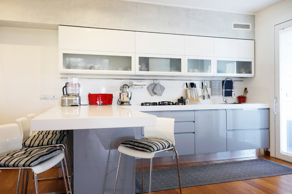 Ispirazione per una cucina a L design con ante lisce, ante bianche, paraspruzzi bianco, penisola, top bianco e pavimento in legno massello medio