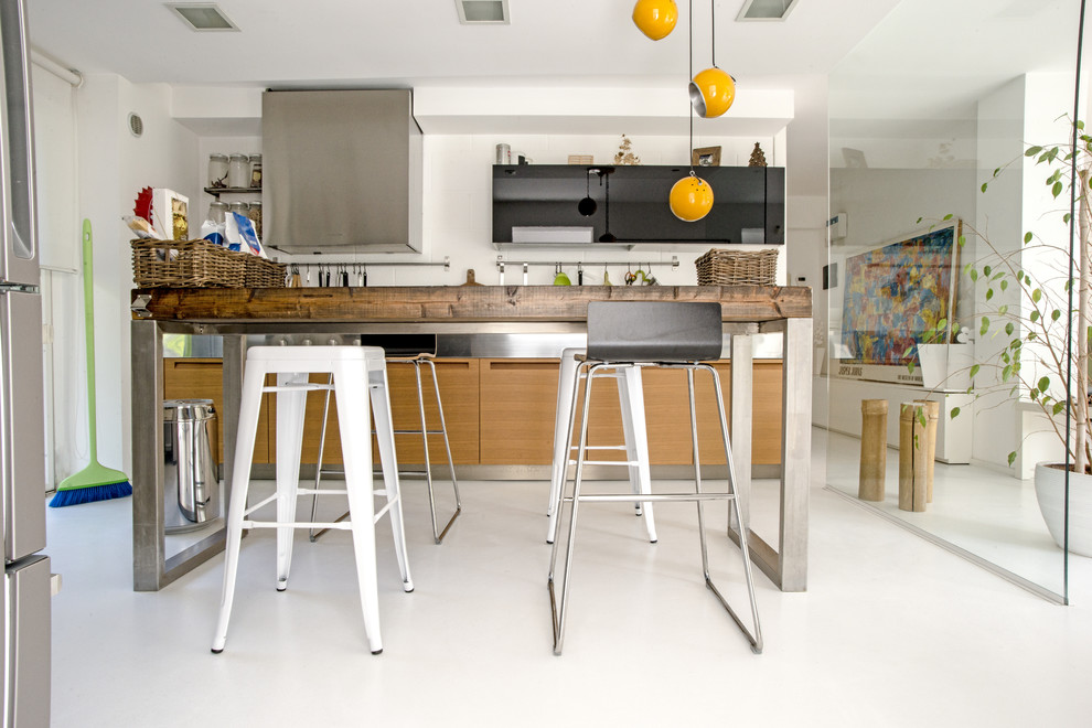 Idee per una cucina moderna di medie dimensioni con lavello da incasso, ante lisce, ante nere, top in acciaio inossidabile e pavimento in cemento