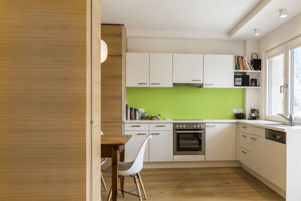 Esempio di una cucina minimalista con ante bianche, paraspruzzi verde, pavimento in legno massello medio, nessuna isola, top bianco, lavello da incasso, ante lisce e pavimento beige