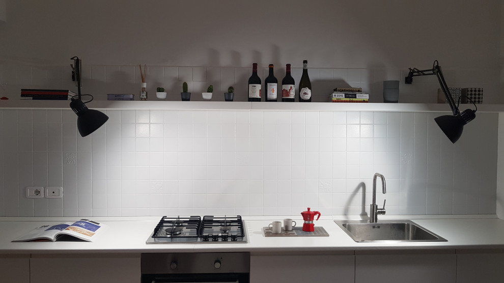 Modern inredning av ett litet vit linjärt vitt kök och matrum, med en enkel diskho, luckor med profilerade fronter, vita skåp, träbänkskiva, grått stänkskydd, stänkskydd i keramik, rostfria vitvaror, betonggolv och grått golv