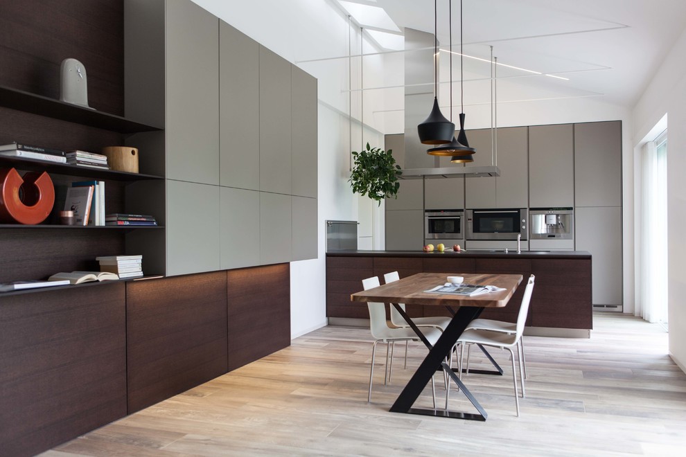 Large modern single-wall kitchen/diner in Venice with flat-panel cabinets, dark wood cabinets, stainless steel appliances, medium hardwood flooring and a breakfast bar.