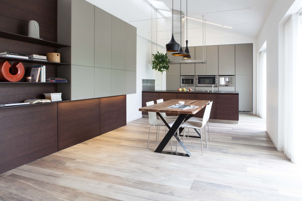 Immagine di una grande cucina minimalista con ante lisce, ante in legno bruno, elettrodomestici in acciaio inossidabile, pavimento in legno massello medio e penisola