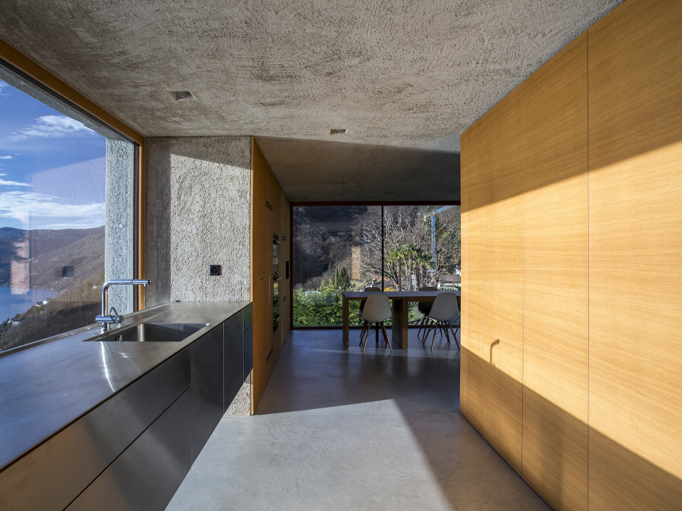 Foto di una cucina parallela minimalista con lavello integrato, ante lisce, ante in legno scuro, pavimento in cemento, nessuna isola, pavimento grigio e top grigio
