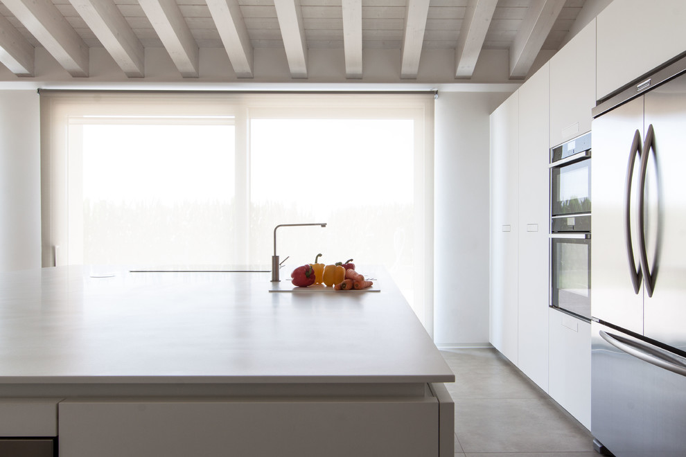 Exemple d'une cuisine ouverte linéaire moderne de taille moyenne avec un placard à porte plane, des portes de placard blanches, un plan de travail en quartz modifié, un électroménager en acier inoxydable et îlot.