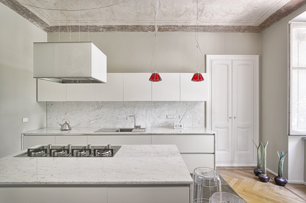 Immagine di una cucina minimal con ante bianche, lavello da incasso, top in marmo, paraspruzzi grigio, paraspruzzi in lastra di pietra e parquet chiaro