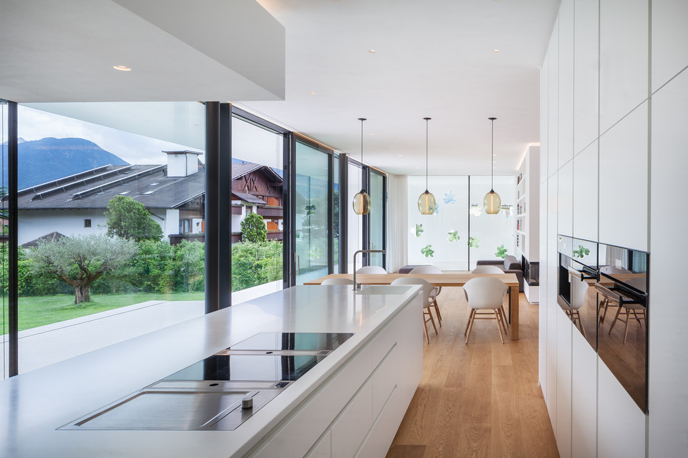 Foto di un cucina con isola centrale minimalista con top in superficie solida, paraspruzzi bianco e top bianco