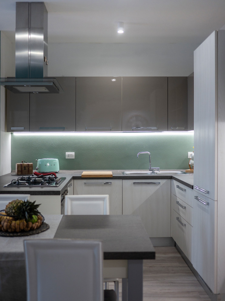 This is an example of a medium sized contemporary u-shaped open plan kitchen in Milan with a double-bowl sink, flat-panel cabinets, beige cabinets, laminate countertops, green splashback, stainless steel appliances, lino flooring, no island, beige floors and grey worktops.