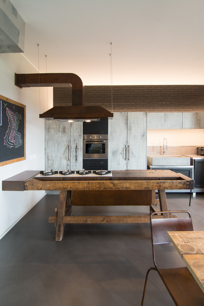 Foto på ett mellanstort industriellt grå kök, med en rustik diskho, luckor med upphöjd panel, grå skåp, bänkskiva i betong, grått stänkskydd, stänkskydd i cementkakel, rostfria vitvaror, betonggolv och en köksö