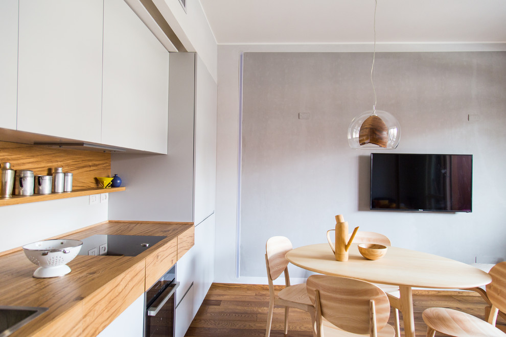 Bild på ett mellanstort funkis linjärt kök och matrum, med en nedsänkt diskho, släta luckor, grå skåp, träbänkskiva, brunt stänkskydd, stänkskydd i trä, mellanmörkt trägolv och brunt golv