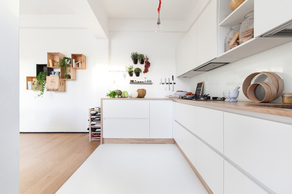 Design ideas for a large contemporary single-wall open plan kitchen in Venice with a built-in sink, flat-panel cabinets, white cabinets, wood worktops, white splashback, porcelain flooring and glass sheet splashback.