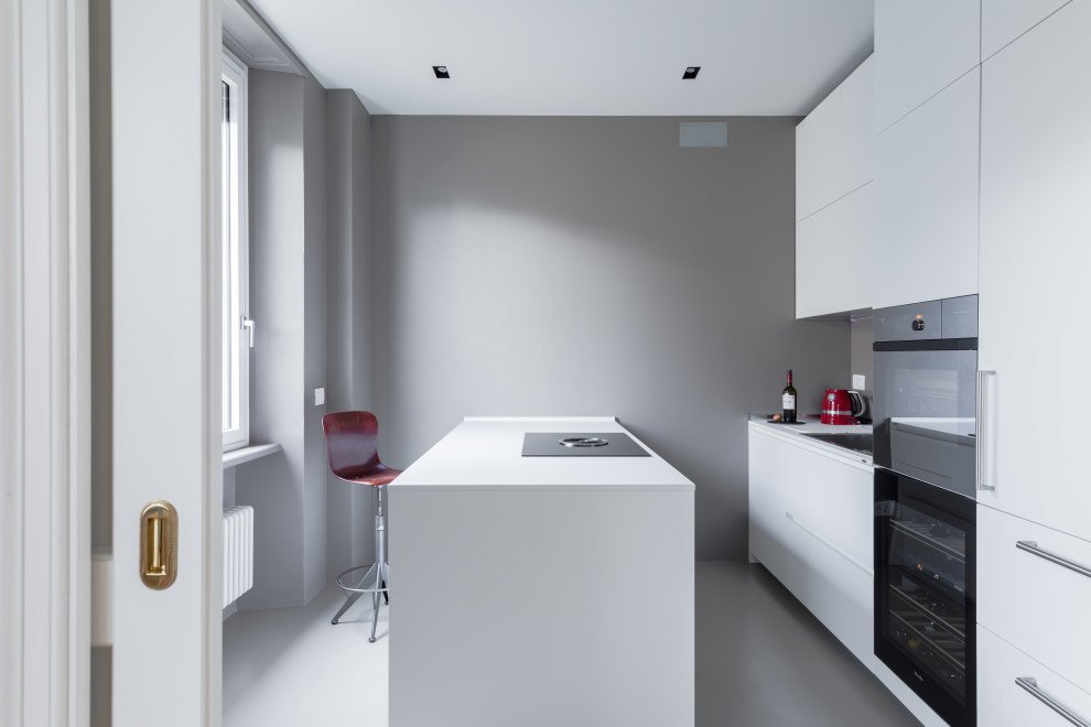 Foto di una cucina moderna con ante lisce, ante bianche, elettrodomestici neri, pavimento grigio e top bianco