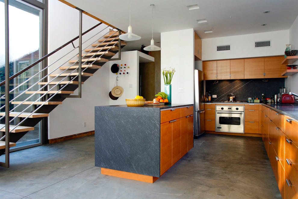Стильный дизайн: большая угловая кухня-гостиная в современном стиле с плоскими фасадами, фасадами цвета дерева среднего тона, бетонным полом и островом - последний тренд