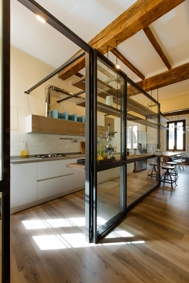 Idee per una cucina minimal di medie dimensioni con ante lisce, ante bianche, paraspruzzi bianco, pavimento in legno massello medio e top grigio