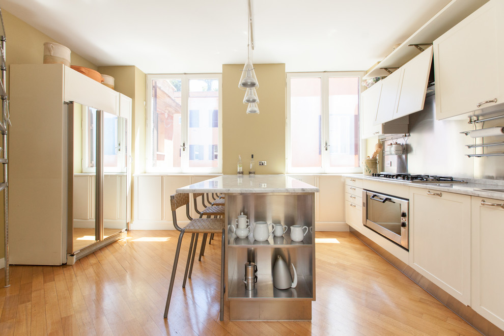 Idéer för ett modernt linjärt kök med öppen planlösning, med luckor med profilerade fronter, vita skåp, marmorbänkskiva, stänkskydd med metallisk yta, stänkskydd i metallkakel, rostfria vitvaror, mellanmörkt trägolv och en halv köksö