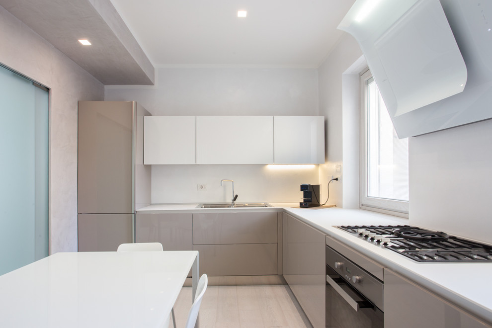 Esempio di una cucina minimal di medie dimensioni con lavello da incasso, ante di vetro, ante beige, elettrodomestici in acciaio inossidabile e parquet chiaro