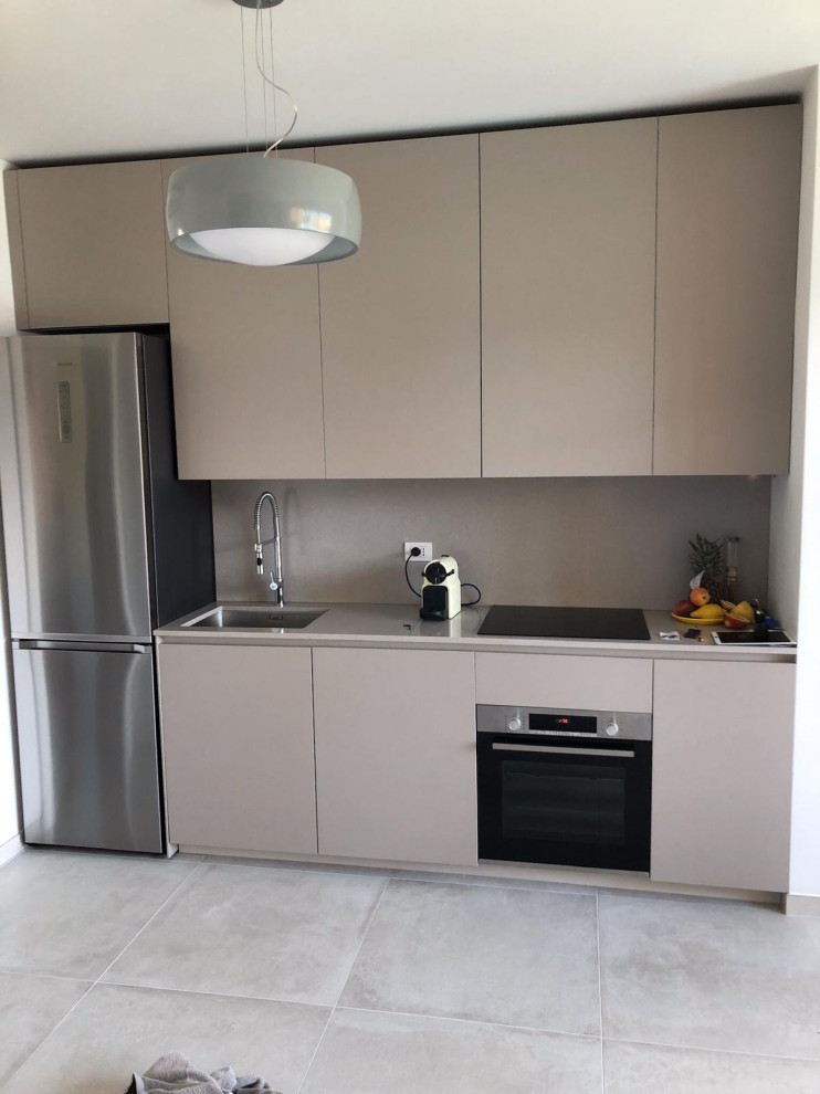 Photo of a small modern single-wall open plan kitchen in Milan with a submerged sink, flat-panel cabinets, beige cabinets, laminate countertops, beige splashback, black appliances, ceramic flooring, no island, grey floors and beige worktops.