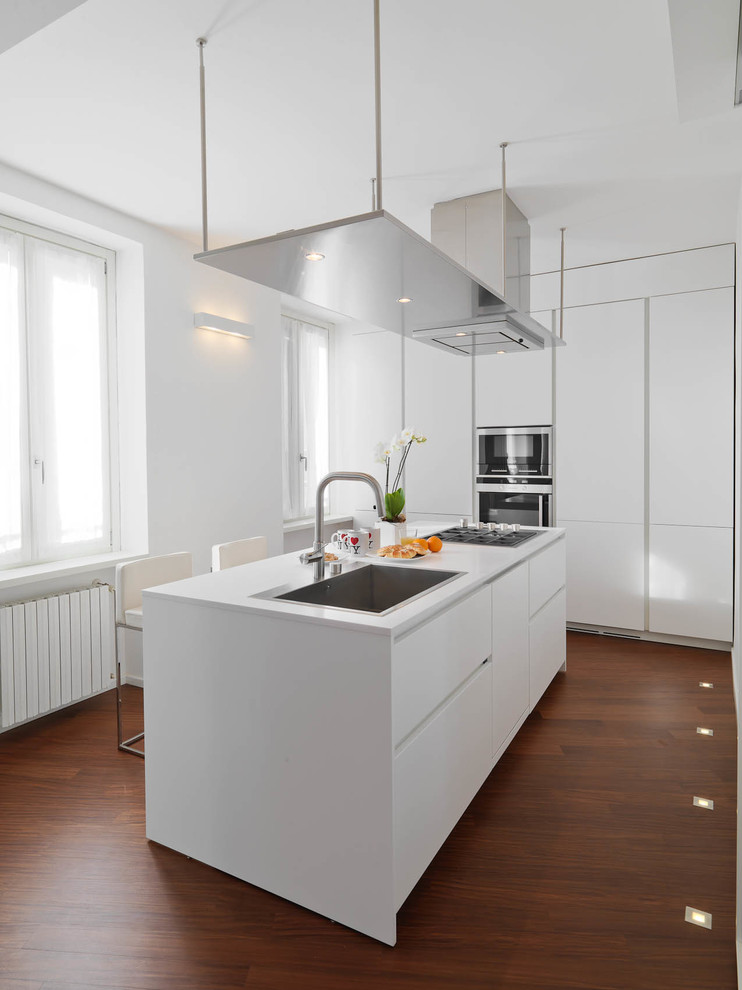 Inspiration for a medium sized contemporary single-wall enclosed kitchen in Milan with flat-panel cabinets, white cabinets, an island, engineered stone countertops, stainless steel appliances, dark hardwood flooring and brown floors.