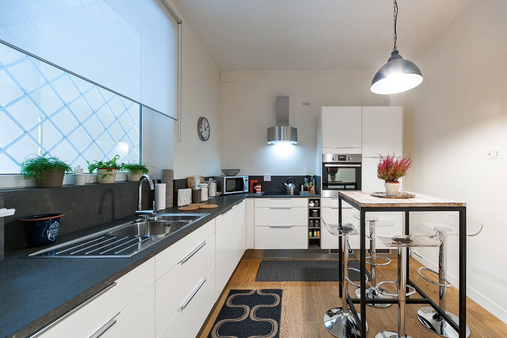 Mittelgroße Moderne Küche ohne Insel in L-Form mit Einbauwaschbecken, flächenbündigen Schrankfronten, weißen Schränken, Küchengeräten aus Edelstahl und braunem Holzboden in Rom