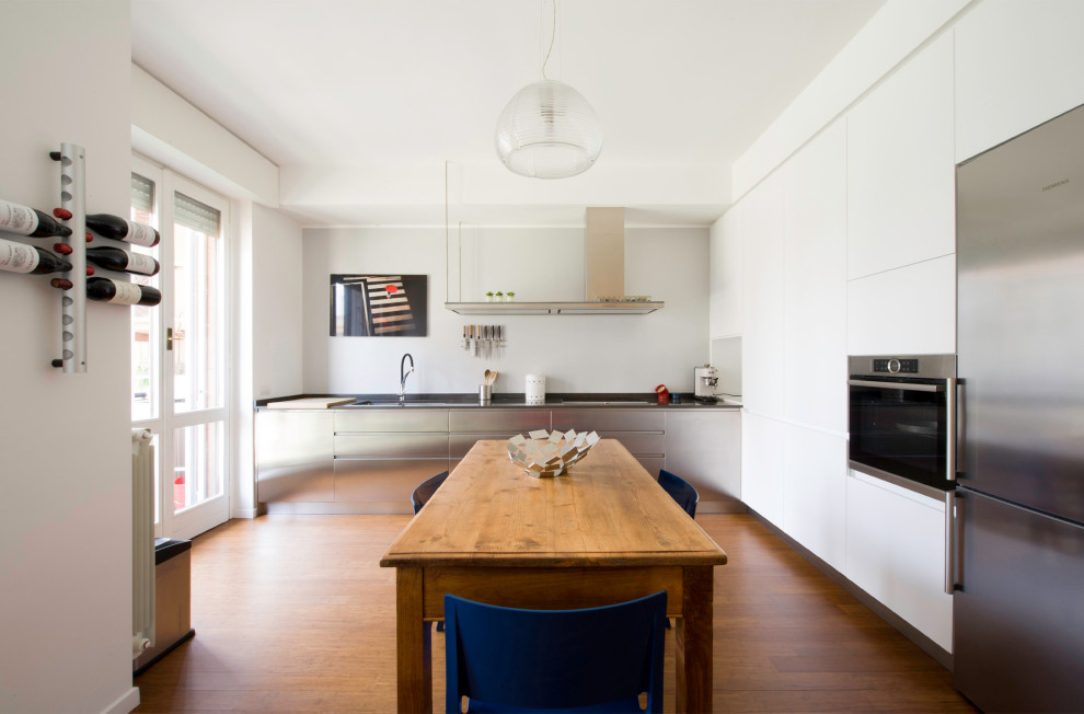 Idéer för ett modernt grå kök, med en undermonterad diskho, släta luckor, vita skåp, rostfria vitvaror, mellanmörkt trägolv och brunt golv