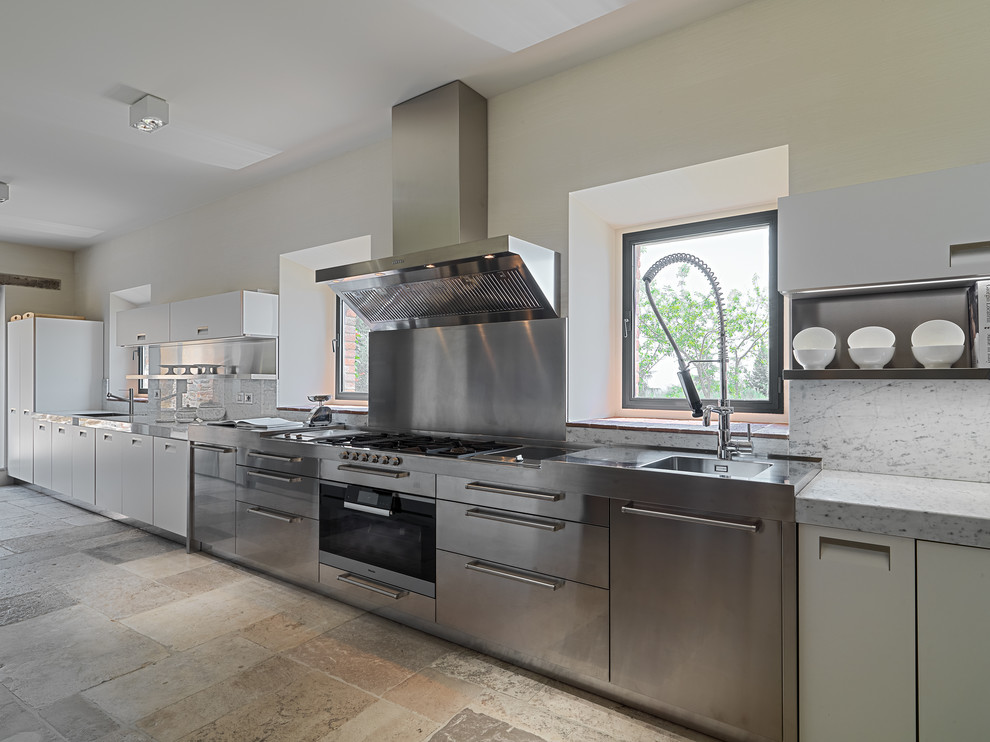 Idee per una cucina moderna con lavello integrato, ante lisce, ante in acciaio inossidabile, top in acciaio inossidabile e pavimento in pietra calcarea