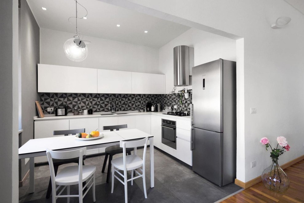 Example of a minimalist l-shaped gray floor open concept kitchen design in Turin with white cabinets, multicolored backsplash, no island and a double-bowl sink
